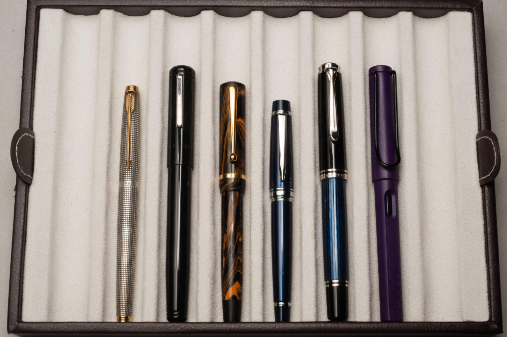 Closed pens from left to right: Parker 75, Franklin-Christoph Model 20, Edison Beaumont, Pilot Stargazer, Pelikan M805, and Lamy Safari